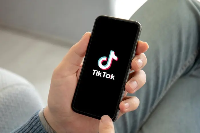 Logos of Microsoft and TikTok against a background of dollar bills