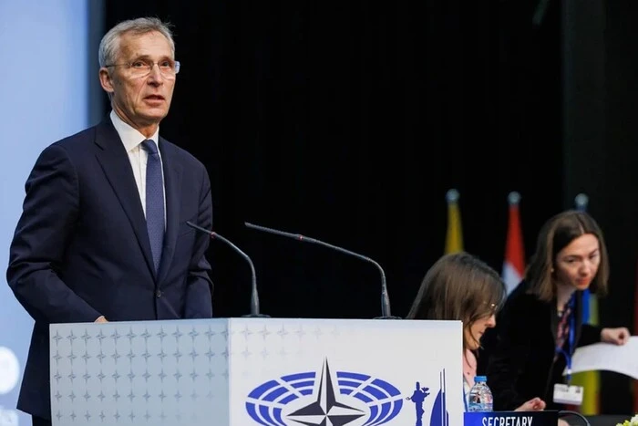 Portrait of Stoltenberg in front of NATO flags